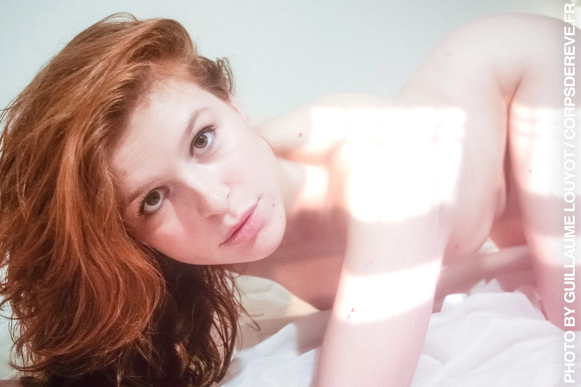 Genia aux cheveux roux, allongée dans une lumière claire
