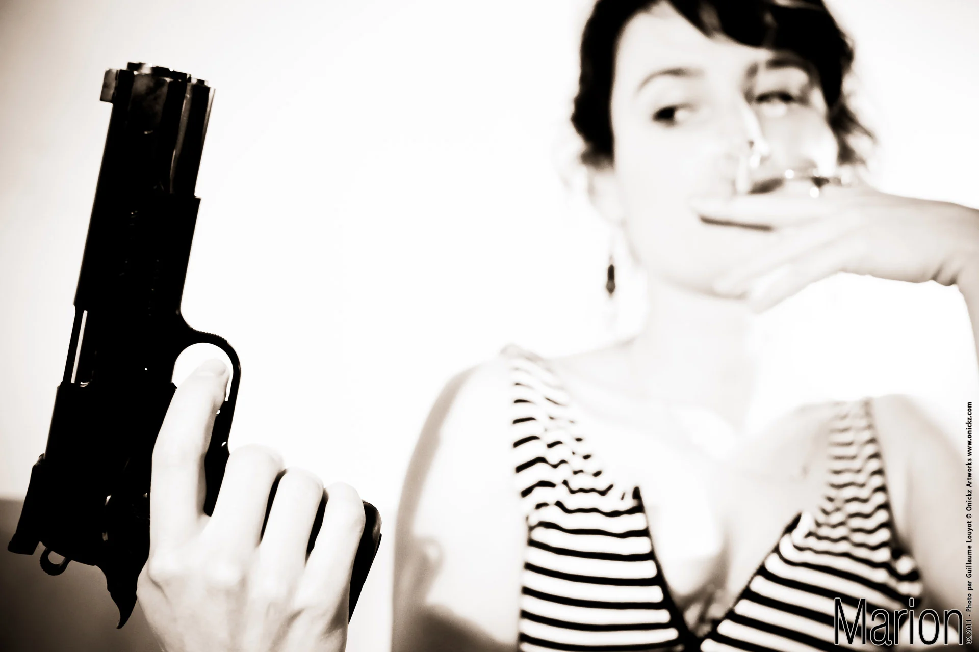 Marion en tenue rayée, tenant un pistolet dans une mise en scène de film noir