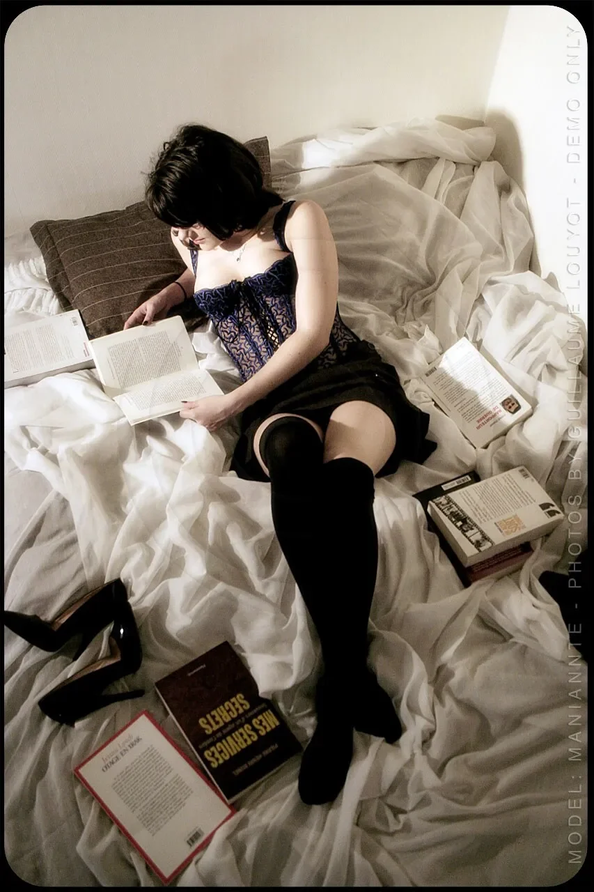 Mademoiselle Chérie assise sur un lit entouré de livres